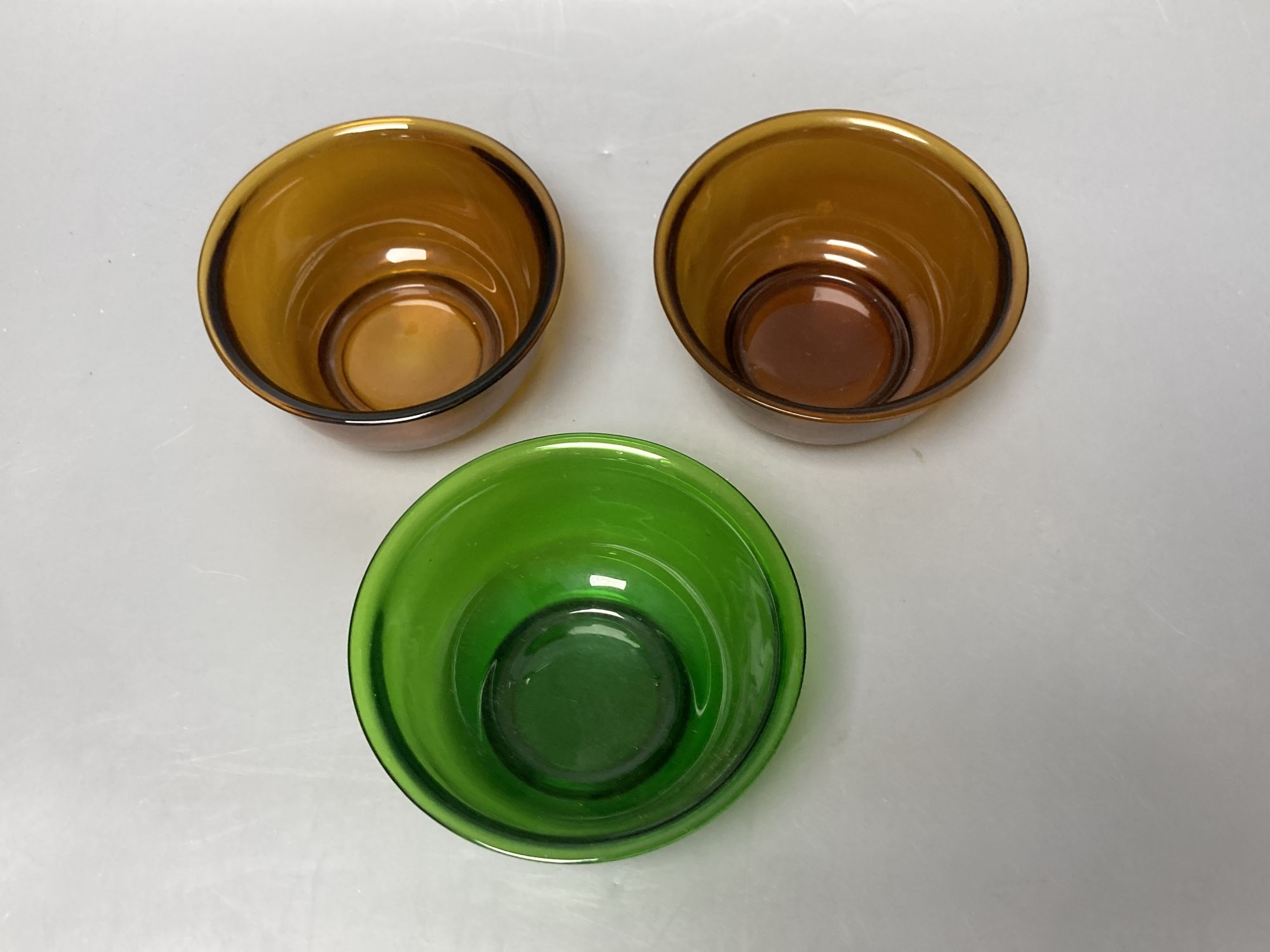 A pair of Chinese Beijing amber glass bowls, together with a similar green glass bowl, diameter 11cm